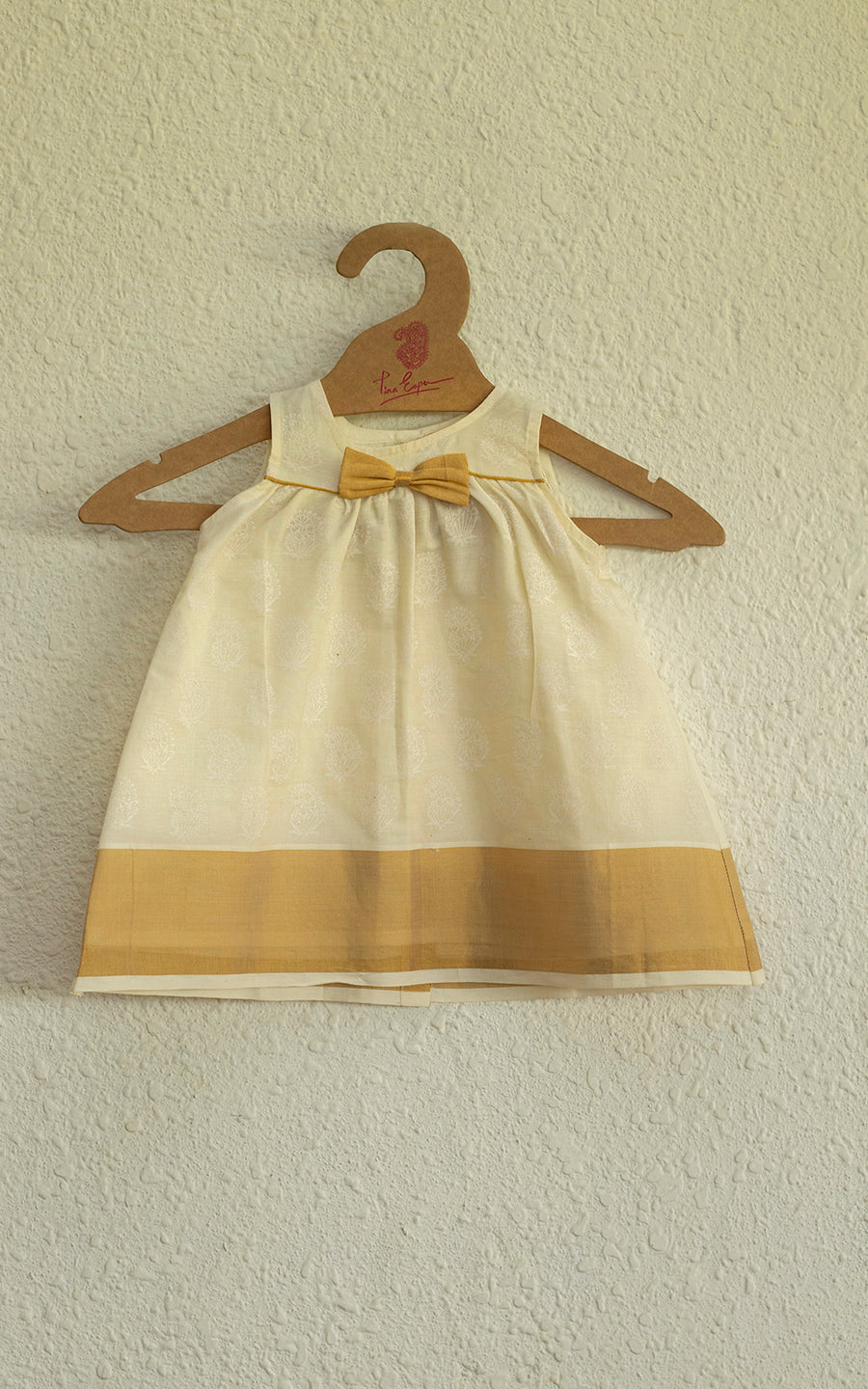 A CHARMING HAND BLOCK PRINTED VINTAGE ONAM DRESS WITH A KASAVY BOW IN PURE COTTON